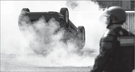  ?? Photog r aphs by I an Langsdon European Pressphoto Agency ?? A VEHICLE is set ablaze in Paris as taxi drivers clash with police during a protest against Uber, the San Francisco- based car service.