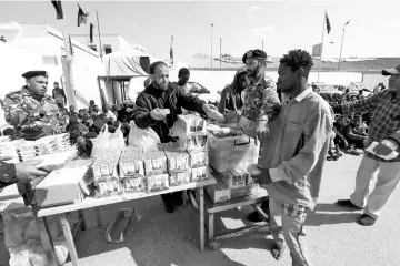  ?? — Reuters photo ?? An African migrant receives food at a detention camp in Tripoli, Libya.