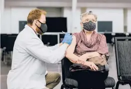  ?? KRISTIAN THACKER/THE NEW YORK TIMES ?? Jake Carr, a student pharmacist, administer­s a coronaviru­s vaccine to Carolyn Zain last week in Charleston, West Virginia.