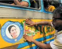  ?? Photo / AP ?? A BJP supporter sticks a party poster showing Babul Supriyo on the side of a public bus beside a poster of West Bengal Chief Minister Mamata Banerjee.