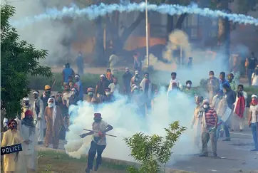  ??  ?? A Pakistani supporter of Canadian cleric Tahir- ul- Qadri returns a teargas shell towards the police during clashes with the security forces near Prime Minister Nawaz Sharif’s residence in Islamabad on Sunday. —