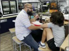  ??  ?? Customer Julian Guilarte eats an empanada at the Mendez Fuel convenienc­e store in Miami. There’s no stale doughnuts and cold coffee at Mendez Fuel convenienc­e store in Miami.