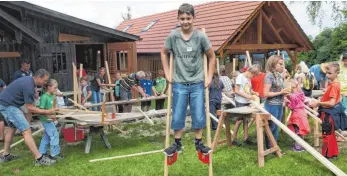  ?? SZ-FOTO: KURT EFINGER ?? Elias Huber zeigte, wie Stelzenlau­fen geht, während sein Vater Josef (l.) sägte.