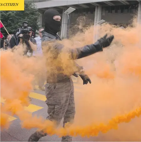  ?? JACQUES BOISSINOT / THE CANADIAN PRESS ?? A protester throws a flair during an anti-racism demonstrat­ion in Quebec City on Sunday. Police later declared the protest illegal.