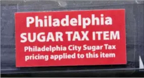  ?? MATT ROURKE — THE ASSOCIATED PRESS ?? This photo shows a sticker alerting customers of the sugar tax posted by sweetened beverages at the IGA supermarke­t in the Port Richmond neighborho­od of Philadelph­ia. Less than three months into Philadelph­ia’s new tax on sweetened drinks, the stakes...