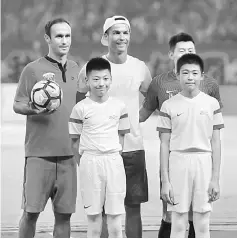  ??  ?? Ronaldo (back, centre) poses with young players before the match between Shanghai SIPG and Guangzhou Evergrande, as part of his individual promotiona­l tour of China, in Shanghai. — AFP photo