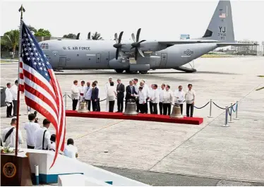  ??  ?? Symbolic handover ceremony: Officials inspecting the bells of Balangiga after their arrival at Villamor Air Base in Pasay, Metro Manila. (Below) Balangiga residents posing with one of the bells following the handover ceremony. — Reuters/AP