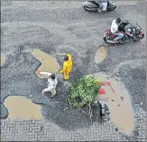  ??  ?? Traffic police at Kapurbawad­i in Thane place a tree branch in a pothole to prevent road accidents.