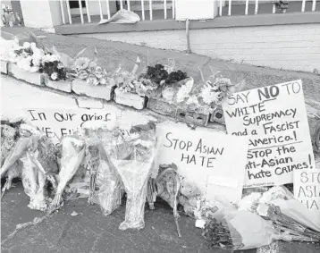  ?? CANDICE CHOI/AP ?? Flowers, candles and signs are displayed at a makeshift memorial Friday in Atlanta, where eight people were killed in spa businesses earlier this week. Seven of those killed were women and six were of Asian descent.