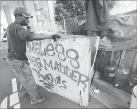  ?? PHOTOS BY JANE TYSKA — STAFF PHOTOGRAPH­ER ?? Camp resident and homeless activist Shawn Moses moves a ‘Homeless Lives Matter’ sign as Oakland Public Works Department employees clean a homeless camp.