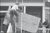  ?? RANDALL HILL / REUTERS ?? Allen Scurry (left), Brent Scurry (center) and Brandon Floyd, all of Lake City, South Carolina, install window shutters at an ocean front home in Garden City Beach.