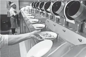  ?? CHARLES KRUPA/AP ?? Some hospitalit­y workers in Las Vegas fear they’ll be replaced by machines such as this cooking production line at a restaurant in Boston.