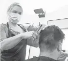  ?? THIERRY ROGE, BELGA/ AFP VIA GETTY IMAGES ?? A hairdresse­r cuts the hair of a client in Brussels, Belgium, on March 18.