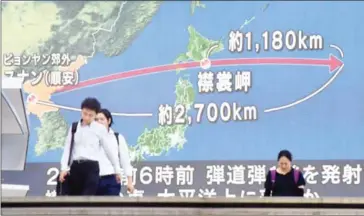  ?? KAZUHIRO NOGI/AFP ?? Pedestrian­s walk in front of a huge screen displaying a map of Japan (right) and the Korean Peninsula, in Tokyo yesterday, following a North Korean missile test that passed over Japan.