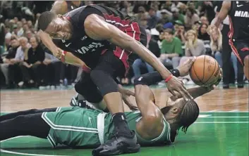  ?? Charles Krupa Associated Press ?? BOSTON CELTICS guard Jaylen Brown, bottom, battles Heat center Bam Adebayo, who added 16 points and eight rebounds, for a loose ball during the first half. Brown finished with 21 points to help the Celtics triumph.
