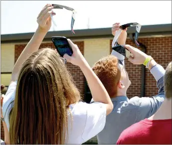  ?? TIMES photograph by Annette Beard ?? Freshmen Mason Plunk and Brenden Power photograph­ed the solar eclipse with their phones through their NASA-approve solar lens. Students who had permission from their parents were issued the glasses and went outside to view the eclipse Monday afternoon.