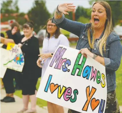  ?? LARRY WONG ?? St. Mary Catholic Elementary School assistant principal Lauren Hawes waves goodbye to students and parents Friday during a drive-by farewell parade in front of the school. The event took the place of the school’s usual end-of-year celebratio­n thanks to the pandemic.