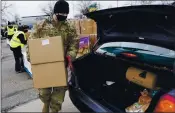  ?? TONY DEJAK — THE ASSOCIATED PRESS ?? Staff Sgt. Mike Schuster loads food into a car at a distributi­on center operated by the Greater Cleveland Food Bank.