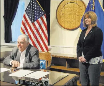  ?? Bill Dentzer Las Vegas Review-Journal ?? Gov. Steve Sisolak speaks Friday after signing an order creating an advisory panel to draft legislatio­n for a compliance board to regulate the marijuana industry. At right is Melanie Young, executive director of the state Department of Taxation.