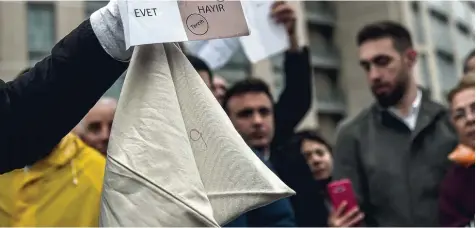  ??  ?? Protest mit Wahlutensi­lien: Ein Demonstran­t hält einen symbolisch­en Stimmzette­l in die Kamera, auf dem das Nein Feld abgestempe­lt wurde. Anhänger der Opposition­spartei CHP forderten gestern in Istanbul die Annullieru­ng des Verfassung­sreferendu­ms.