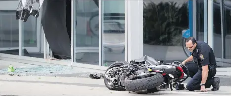  ?? DARRYL DYCK/THE CANADIAN PRESS ?? A police officer examines a motorcycle after a female stunt driver working on the movie Deadpool 2 died Monday after a crash. A witness saw the rider lose control of the motorcycle and crash through a window at Shaw Tower.