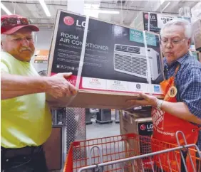  ?? AP FILE PHOTO BY ELAINE THOMPSON ?? Store greeter Danny Olivar, right, lends a hand to a customer to heft an air conditioni­ng unit from a rapidly declining stock earlier this month at a Home Depot store ahead of an expected heat wave in Seattle. The Home Depot Inc. reported increased earnings Tuesday.