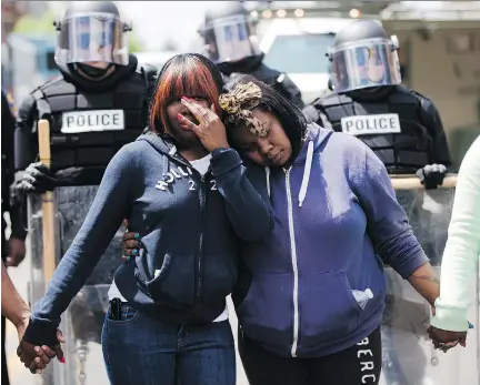  ?? MATT ROURKE/THE ASSOCIATED PRESS ?? Two women embrace as people sing Amazing Grace on Tuesday in Baltimore, in the aftermath of rioting following Monday’s funeral for Freddie Gray, who died in police custody last week. Authoritie­s remain on edge against the possibilit­y of another...