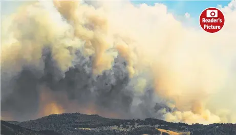  ?? Picture: NICK MONK ?? XXXXXXXXXX: A water bombing helicopter is a speck in the clouds of smoke at Glen Huon,