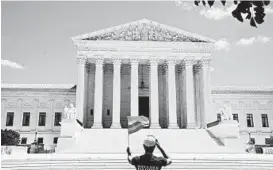  ?? ANNA MONEYMAKER/THE NEW YORK TIMES ?? A person waves a rainbow flag Monday in front of the Supreme Court in Washington.