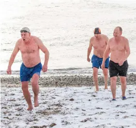  ?? PHOTO: NAOISE CULHANE ?? Feeling the chill: Swimmers Jim Curran, Liam Walsh and Lorcan Byrne brave the icy waters and snowy beach at Bray.
