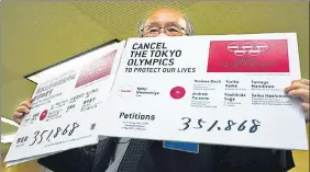  ?? AP ?? A representa­tive of an anti-Olympics group holds boards showing the number of people who have signed a petition calling for the cancellati­on of Tokyo 2020.