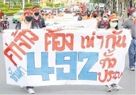  ?? ?? Workers hold signs calling for a daily minimum wage of 492 baht at Democracy Monument on Labour Day, May 1.