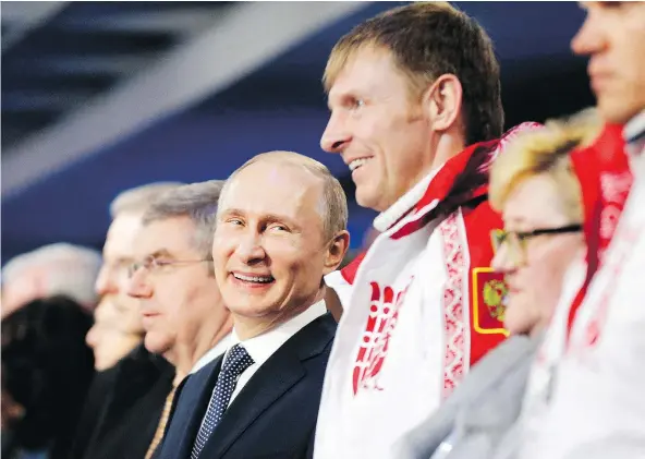  ?? — GETTY IMAGES FILES ?? President Vladimir Putin stands next to Alexander Zubkov, a Russian bobsled gold medallist, during the closing ceremonies at the Sochi Winter Games. Zubkov was recently banned for life from the Olympics and had his medals stripped for doping violations.