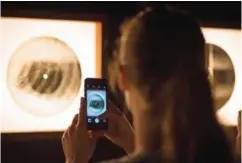  ??  ?? A visitor takes a photo of a music recording on an X-ray film is displayed at the Bone Music exhibition at Garage Museum of Contempora­ry Art.