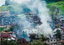  ??  ?? MARAWI, Philippine­s: Smoke billows from burning houses as fighting between government troops and Islamist militants continues in Marawi on the southern island of Mindanao yesterday. —AFP