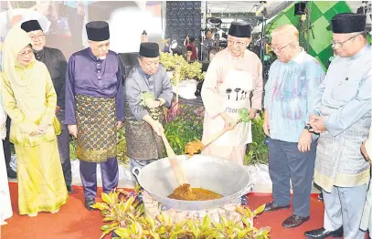  ?? ?? SAJIAN TRADISI: Abang Johari (tiga kanan) bersama Haidar menggaul rendang daging sebagai gimik perasmian Majlis Ramah-Tamah Aidilfitri Bersama YAB Premier di Naim Street Mall Bintulu Paragon, semalam.