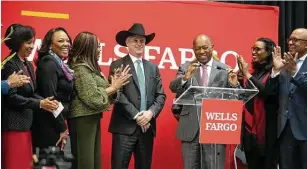  ?? Mark Mulligan / Staff photograph­er ?? Members of the board of the Houston Fund for Social Justice and Economic Equity applaud as Wells Fargo CEO Charlie Scharf puts on a cowboy hat given to him by Mayor Sylvester Turner.