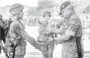  ?? — Gambar Bernama ?? TAHNIAH: Zamrose (kanan) menyampaik­an piala kepada perajurit muda Keseluruha­n Terbaik Mohamad Nor Farhan Mahzal pada acara Perbarisan Tamat Perajurit Muda Lelaki Siri 194/21 dan Wanita Siri 47/21 di Pusat Latihan Asas Tentera Darat (PUSASDA), Port Dickson semalam.