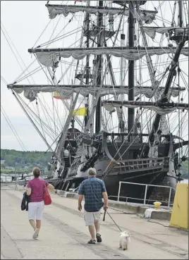  ?? SALTWIRE NETWORK ?? A couple and their dog walk past El Galeon, a full-rigged Spanish ship, on Monday at Pier C in Pictou. The vessel was one of five tall ships that stopped in the Shiretown as part of Rendez-Vous 2017 over the weekend.