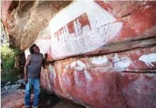  ??  ?? Traditiona­l owner Johnny Read examines an image of a European vessel drawn between 1870 and 1920. Shielded by a rocky overhang, this gallery, 100km from the coast, is dominated by saltwater themes including images of a whale, birds and boats.