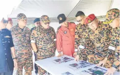  ?? ?? KENAL PASTI: (Dari kanan) Ramlan ketika memberi taklimat kepada Khirudin pada lawatan Operasi Pemadaman Kebakaran Gambut di Banting Lawas, kelmarin dan turut kelihatan Azman.