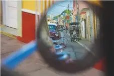  ??  ?? Above: street scene in the Cuban town of Trinidad viewed from a taxi wing mirror. Left: buying fresh provisions from a Trinidad street seller