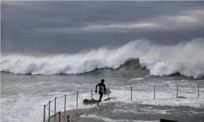  ?? Photograph: Blake Sharp-Wiggins/The Guardian ?? A surfer runs towards the water at Bronte beach in Sydney on Wednesday morning as huge surf andwild weather lashed parts of the NSW coast.