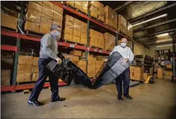  ?? Allen J. Schaben Los Angeles Times ?? SALAM I NTERNATION­AL Vice President David Cameron, left, and owner Abdul Salam unpack a body bag at their warehouse in Laguna Hills.