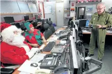  ?? POSTMEDIA NETWORK FILE PHOTO ?? Santa and an assistant elf get their pre-flight operationa­l briefing from Lieutenant-Colonel Darrell Marleau, Combat Operations Division Chief, before their flight through Canadian Airspace in this 2014 photo.