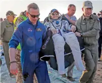  ?? AFP ?? Ground personnel carry Peggy Annette Whitson after she landed via the Soyuz MS-04 capsule in a remote area outside the town of Dzhezkazga­n (Zhezkazgan), Kazakhstan on Sunday. —