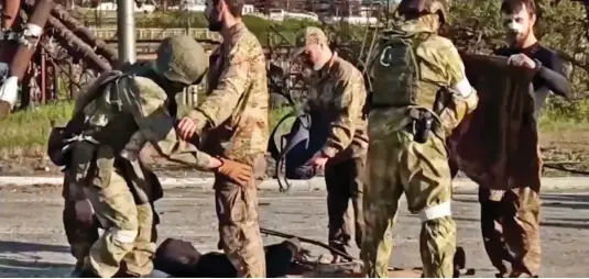  ?? ?? Searched: Russian troops frisk Ukrainian soldiers yesterday as they are evacuated from the Azovstal steelworks