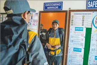 ??  ?? Rangdol gets ready to deliver packages at an Amazon logistical office in Leh. Amazon requires him, and all of its drivers, to wear closed-toe shoe, be neatly groomed, display their ID cards and carry a fully charged cellphone.
