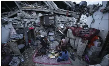  ?? Fatima Shbair/Associated Press ?? Members of the Al-Rabaya family break their fast Monday during the Muslim holy month of Ramadan outside their home, which was destroyed by Israeli airstrikes, in Rafah, Gaza Strip.