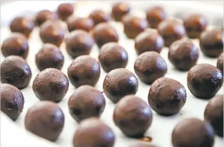  ?? PHOTOS BY GABRIELA CAMPOS/THE NEW MEXICAN ?? ABOVE: A tray of freshly rolled pomegranat­e truffles await another layer of chocolate Tuesday at Kakawa Chocolate House’s new location at 1300 Rufina Circle, Suite A4. BELOW: An array of Kakawa’s artisanal chocolates.